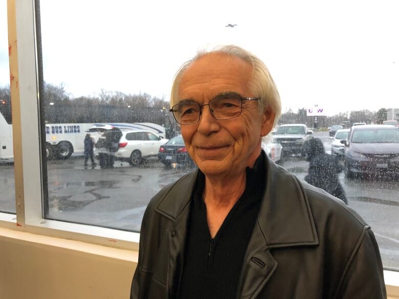 An older man standing near a window.