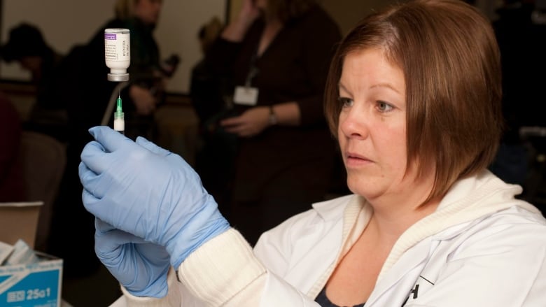 A female health-care professional prepares a dose of the H1N1 influenza vaccine in 2009. 