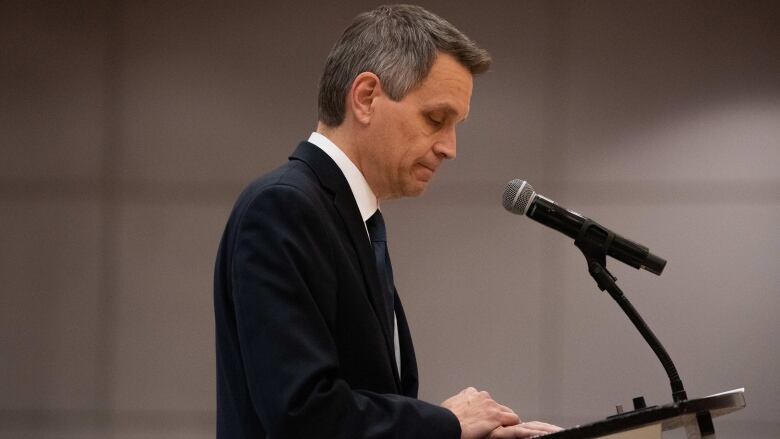 A politician looks down at his lectern while speaking.