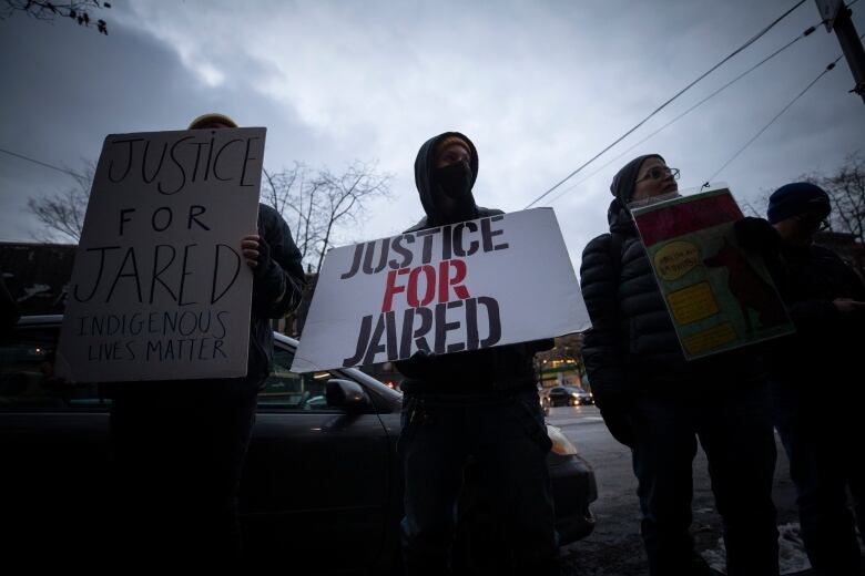 A person at a rally holds a hand-made sign that says 