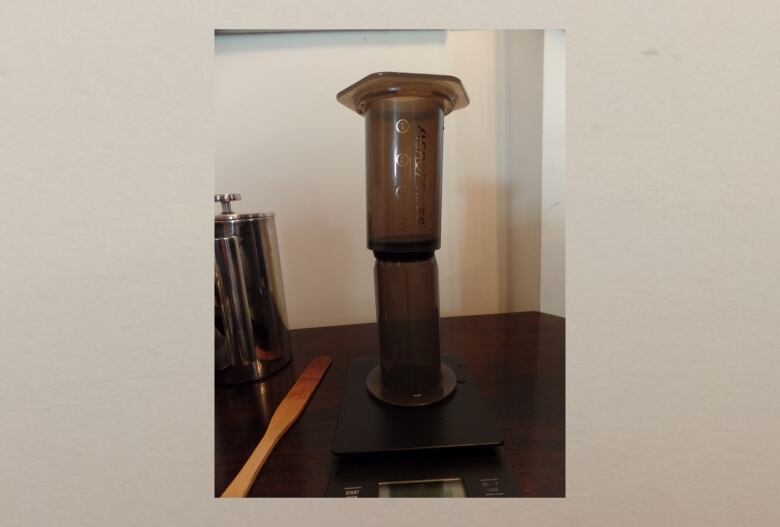 An AeroPress, a cylindrical tool used to make coffee, is pictured on a table.