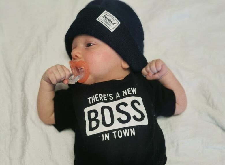 A young baby wearing a T-shirt and cap.