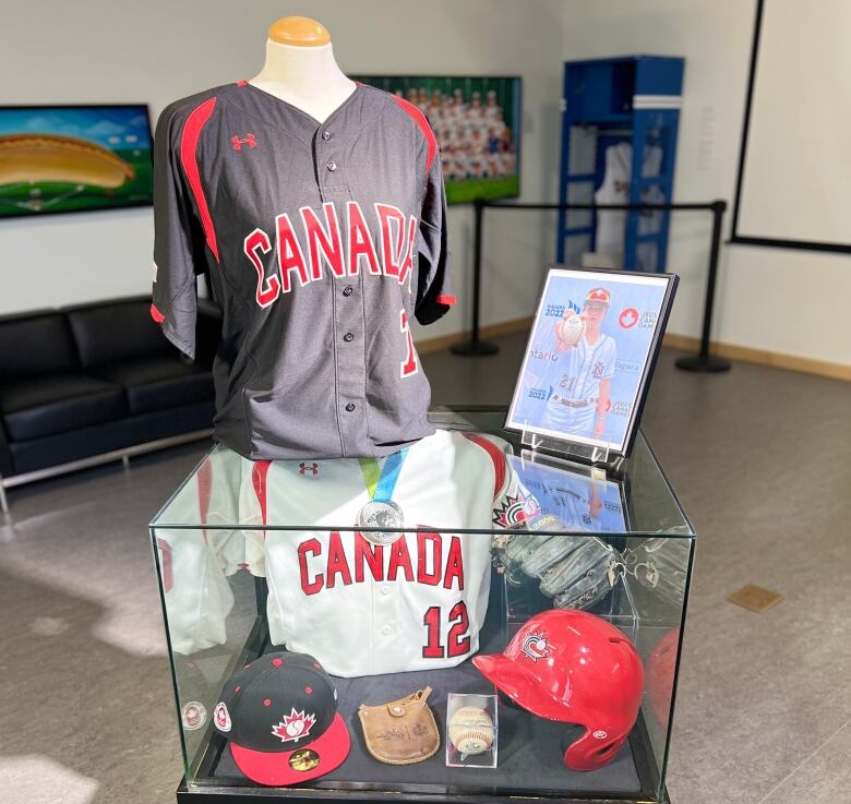 A display case with baseball hats, jerseys and a baseball in the middle.