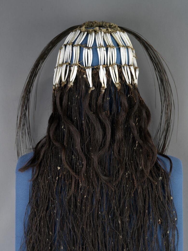 A headdress with flute-shaped seashells, baleen from humpback whales and long braided hair.