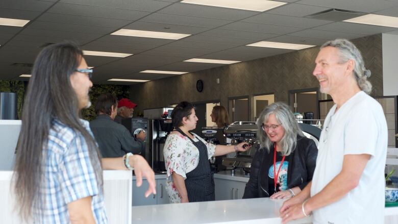 A number of people talk around a cafe counter.