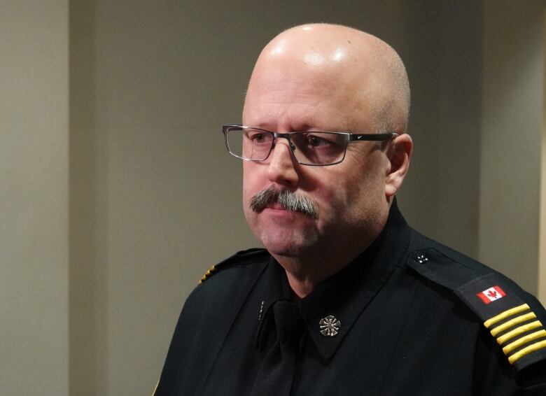 A man with a mustache and glasses wearing a fire department uniform, seen from the shoulders up.