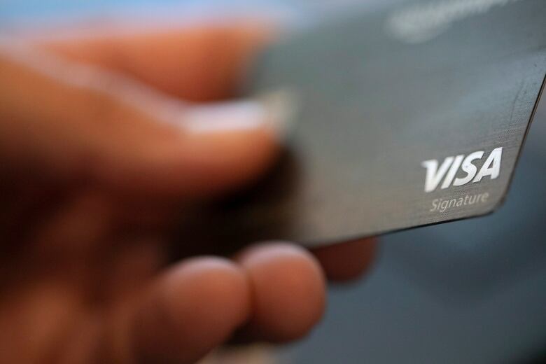 Hand holding a Visa card.