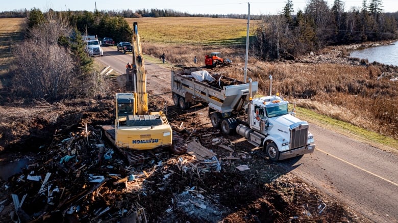 Heavy equipment scooping up debris left by Fiona into trucks to be taken away 