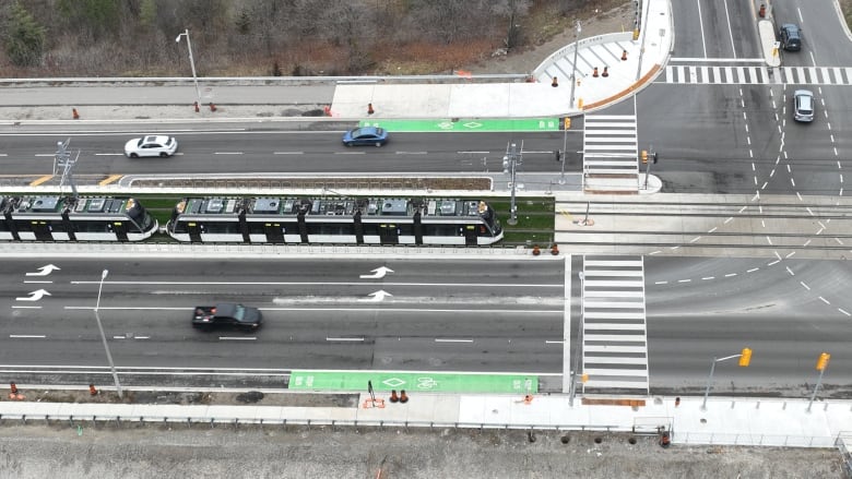 A train is seen from overhead moving along a city street.