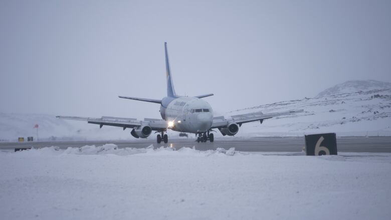 A plane on tarmac in the winter time.