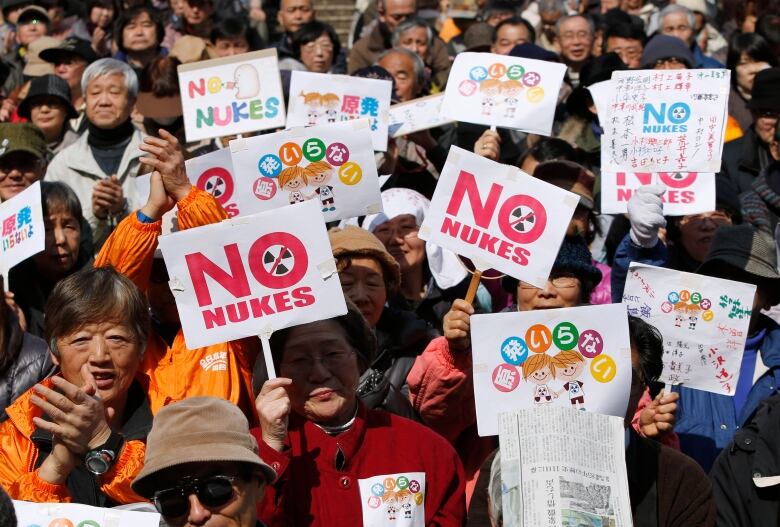 A large group of protesters hold signs.