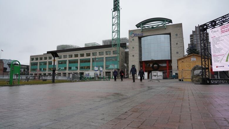 People walk outside an institutional building on a gloomy day.