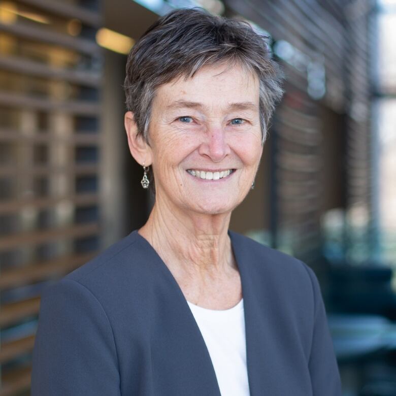 A smiling woman with a dark vest.