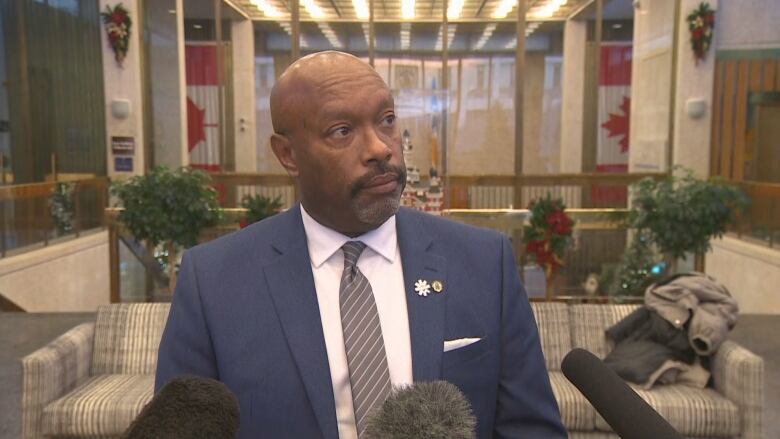 A man in a suit stands inside the council building at city hall.