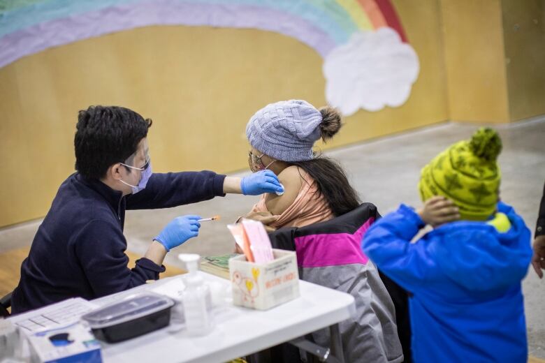 A child receives her influenza vaccine with her family at a Fraser Health vaccination clinic in Surrey, B.C., on Wednesday, Dec. 7, 2022. 