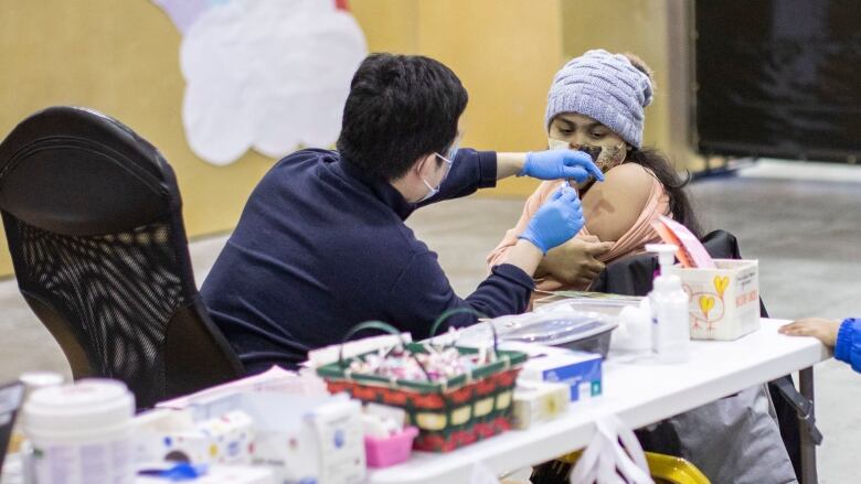 A child receives her influenza vaccine with her family at a Fraser Health vaccination clinic in Surrey, B.C., on Wednesday, Dec. 7, 2022.