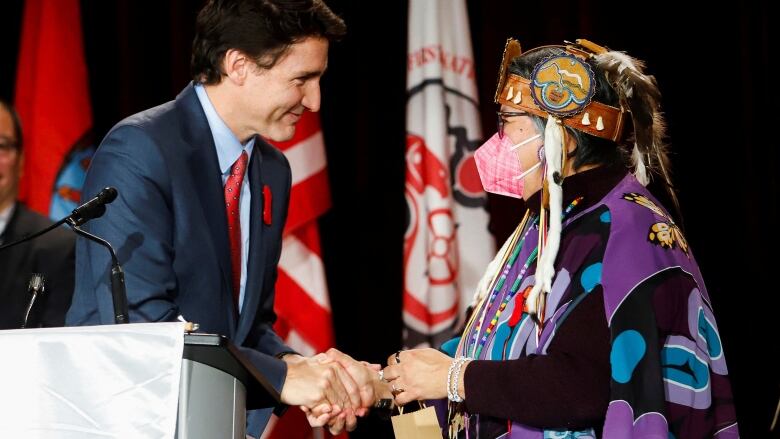 Two political leaders shake hands on a stage.