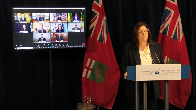 Heather Stefanson stands at a podium, in front of a monitor showing 10 other people in separate windows.