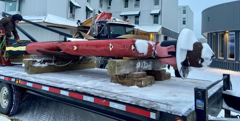 Wooden mountie statue laying flat on a flatbed truck