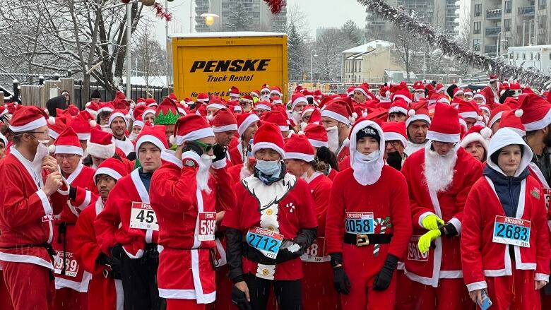 A snowy 5K race starting line with a large group of people dressed as Santa Claus