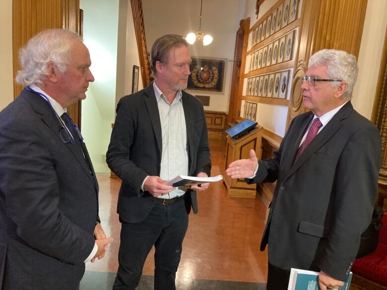 Three men speaking to each other