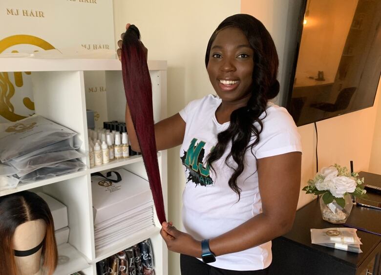 A woman holding a hair extension. 