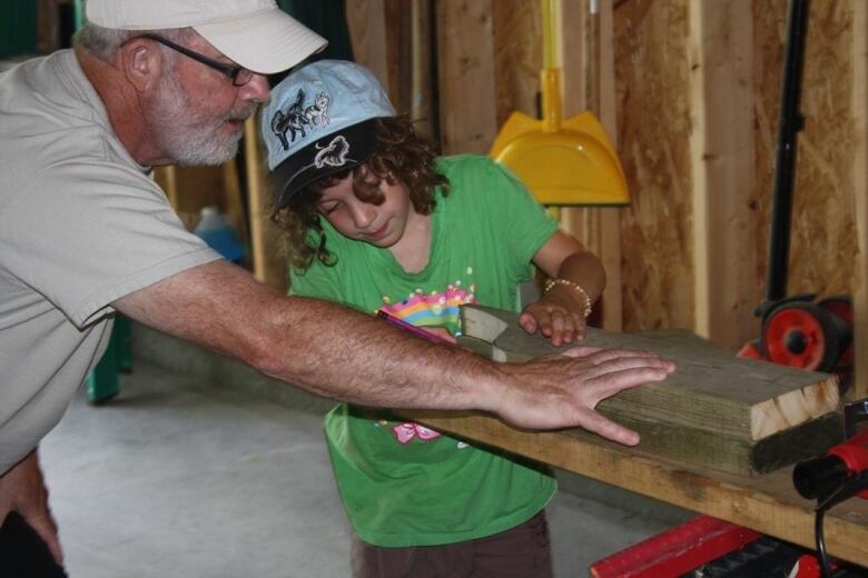 A man and a young girl work together in a workshop.