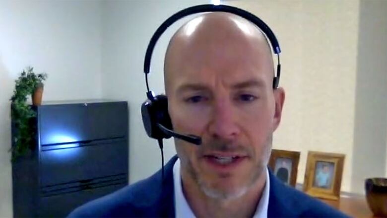 A profile of a man in an office, wearing a headset.