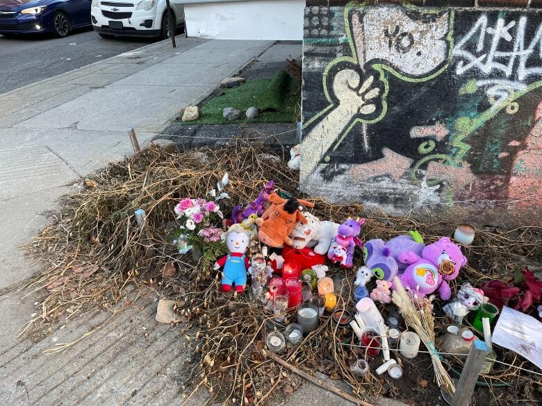 Candles and stuffed animals lie on the ground. 