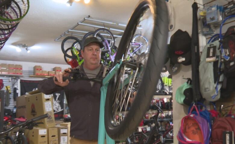 Man holds a bike in a bike shop 