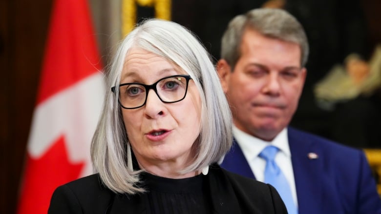 A woman with glasses speaks to media in the foyer of the House of Commons on Parliament Hill in Ottawa. 