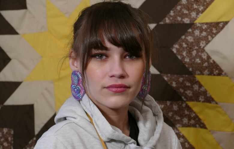 Portrait of a woman in front of a quilted blanket.