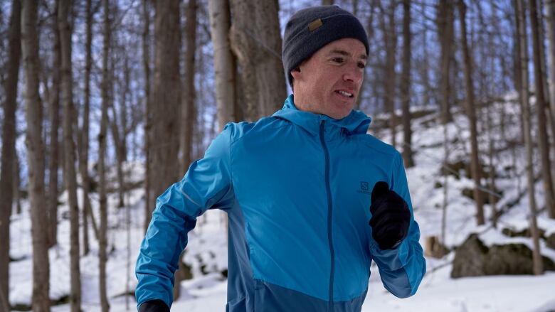 A man runs in a forest in the winter.