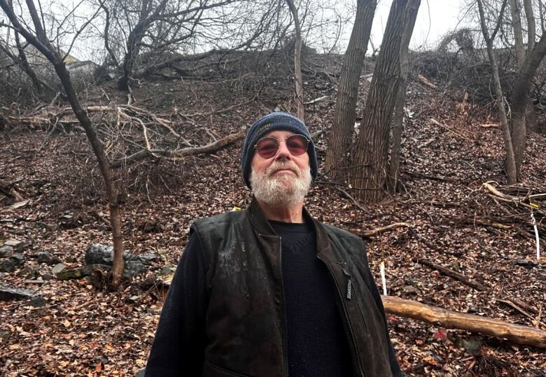 A man in a toque and sunglasses is seen in a park.