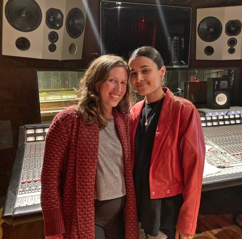 Two smiling women stand in a recording booth.