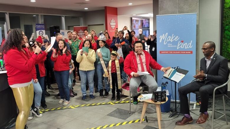 More than two dozen people cheer and clap in the lobby of CBC Calgary as host Jenny Howe announces that the fundraising goal was met. 