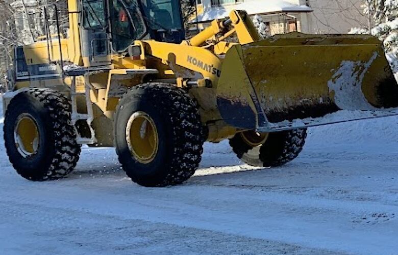 A front-end loader cleans a snowy street