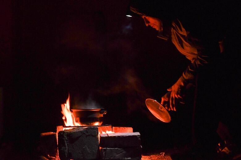 A man cooks food over an outdoor fire during a blackout in Ukraine