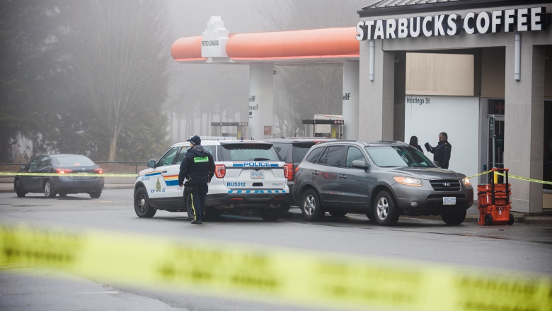 Police tape, an RCMP SUV and a police officer are seen around a Starbucks parking lot.