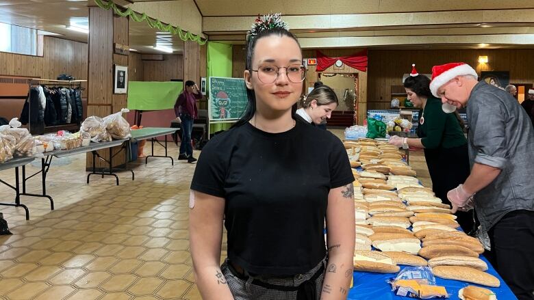 A young woman is pictured in front of a table of food. 