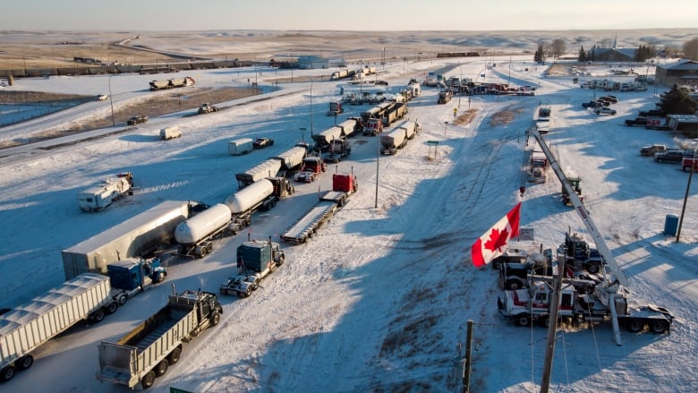 an aerial view of a line of trucks parked on a snowy road