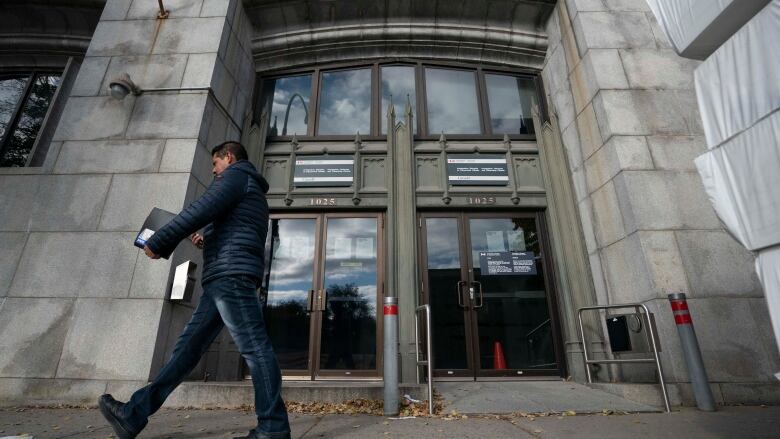 A man walks by a building with a sign.