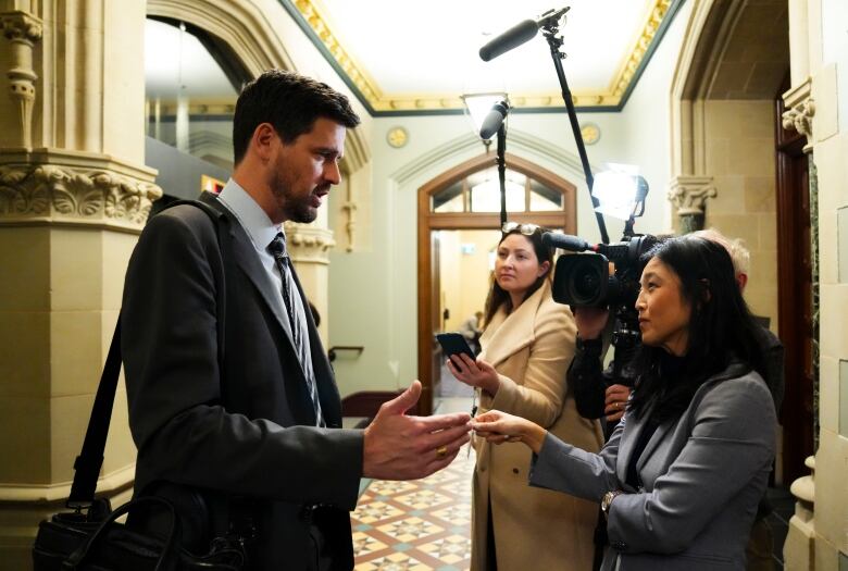 A man speaks with reporters inside a building.