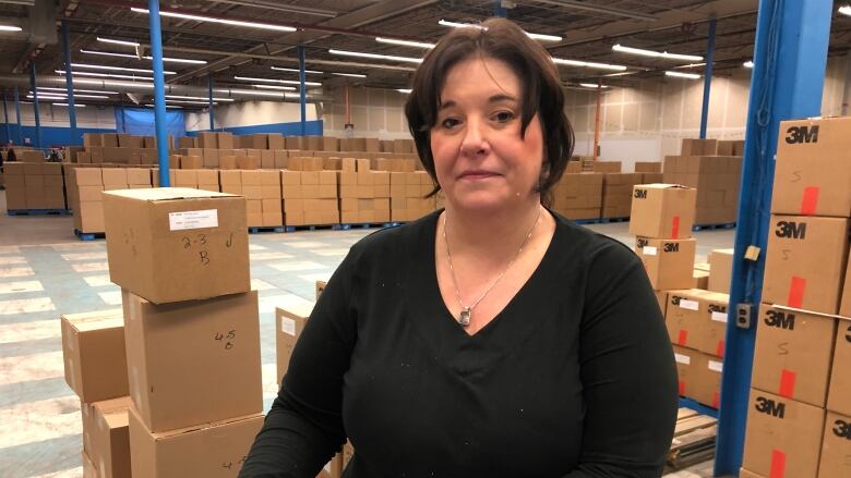 A lady stands with a clipboard in her hands in a warehouse.