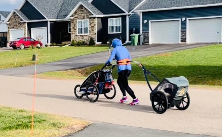 A woman running while pushing and towing a stroller.