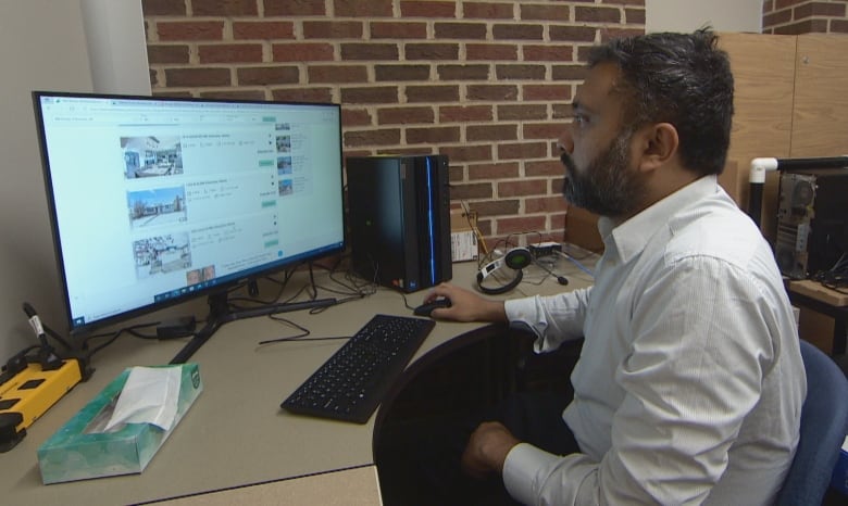 A man searches real estate listings on his computer.