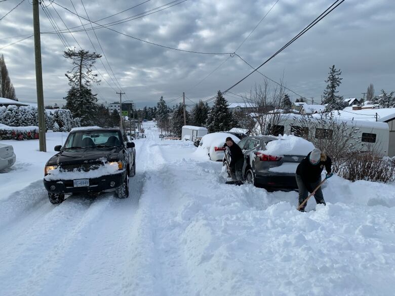 Two people shovel around cars in Victoria, B.C.