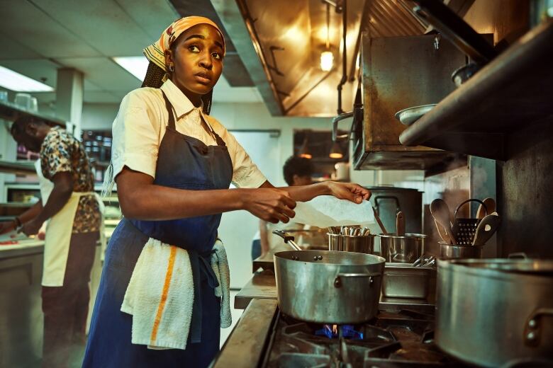 Woman cooking in restaurant kitchen.