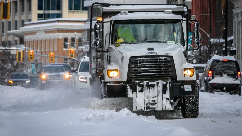 A large snowplow drives down the street