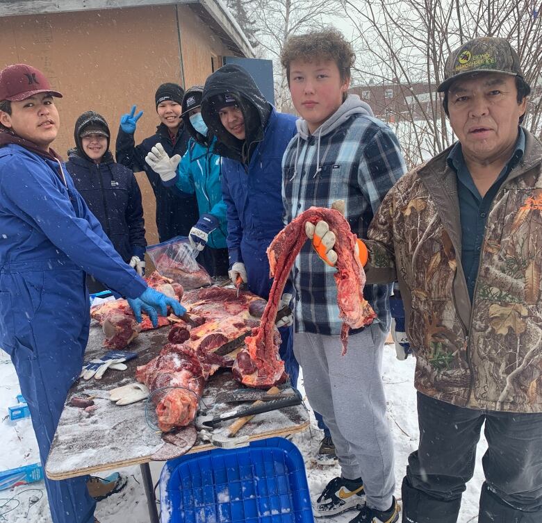 Students and community members prepare meat together in Behchok.